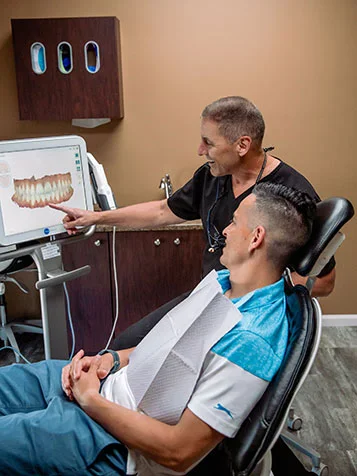 A dentist showing a patient a 3D scan of his teeth on screen